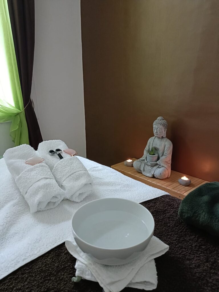 Table de soin pour une séance de Kobido,ambiance zen avec bougies, statue de Bouddha et accessoires de massage
