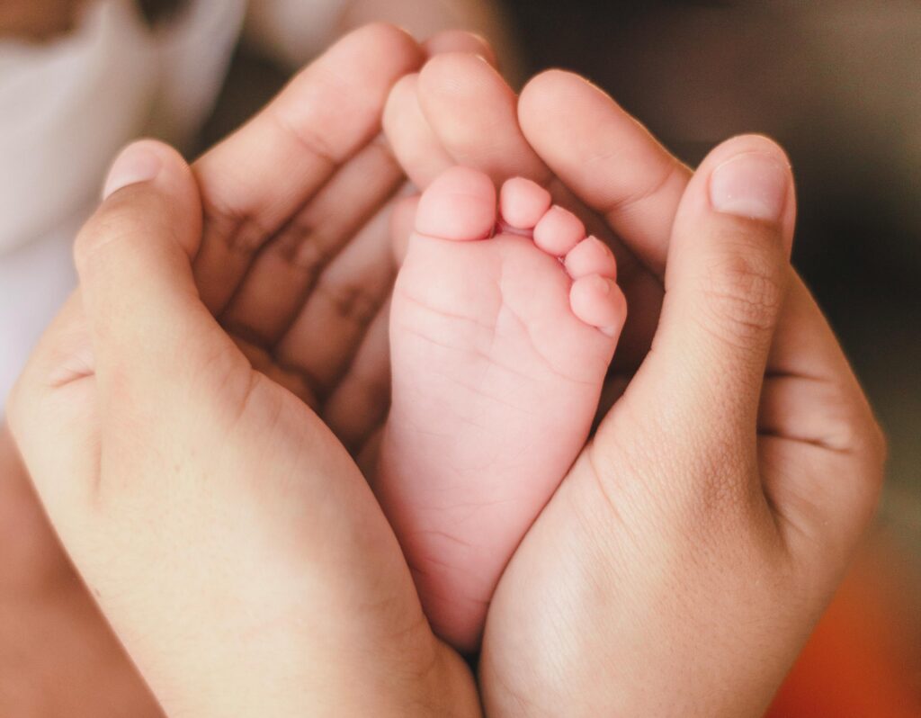 Petit pied de bébé enveloppé dans les mains d'un parent